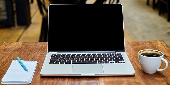 Laptop mit Notizblock und Kaffee