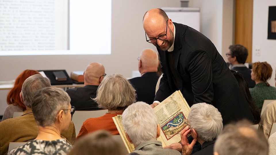 Noah Regenass, Bereichsleiter Historische Sammlungen, zeigt dem Publikum ein Sammlungsstück aus den Beständen der UB.